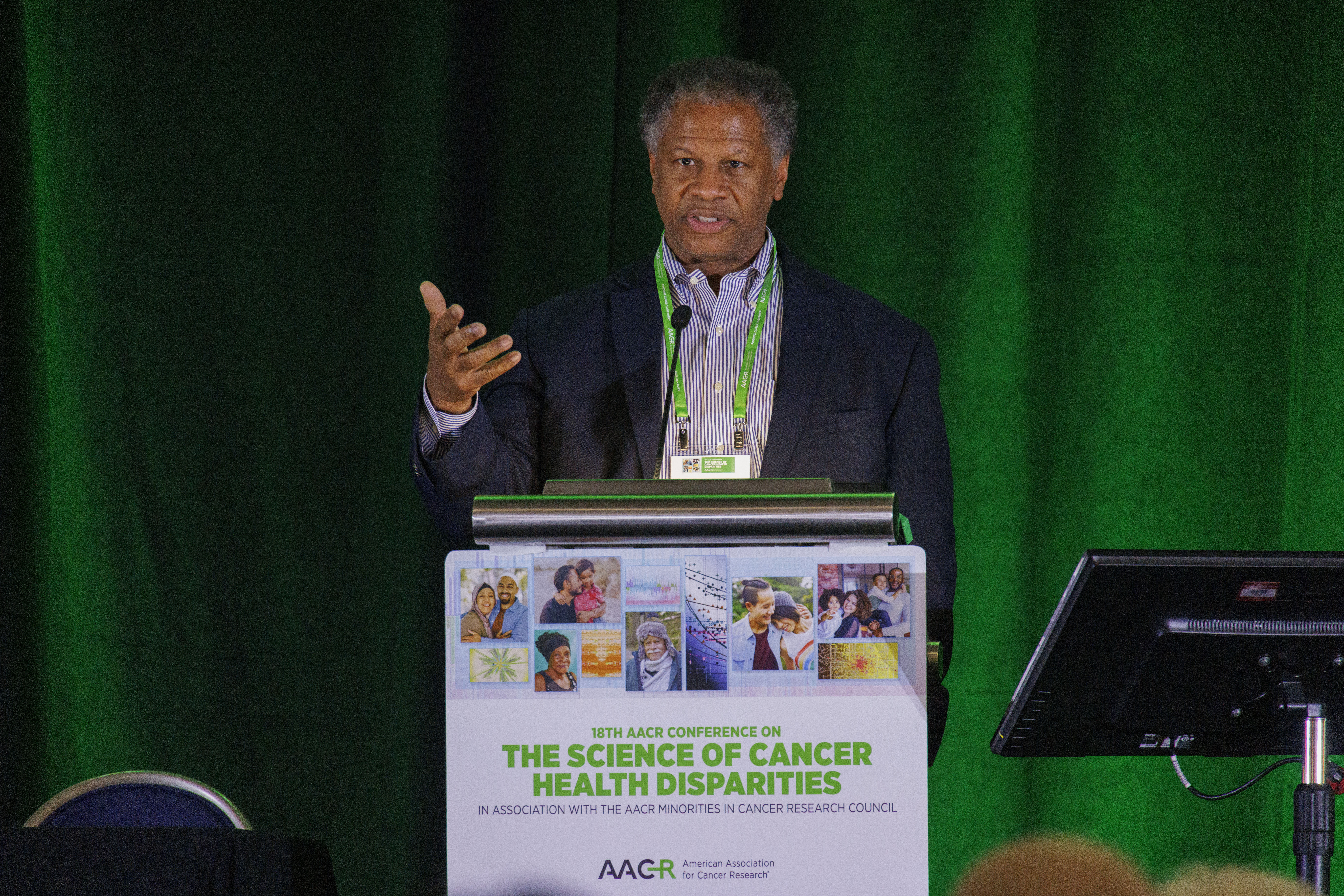 DR Robert Winn standing at podium speaking with green overhead lights