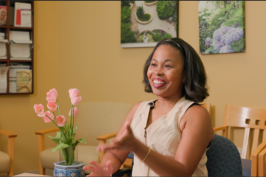 Tasha Cade smiling and talking to subject who is off camera